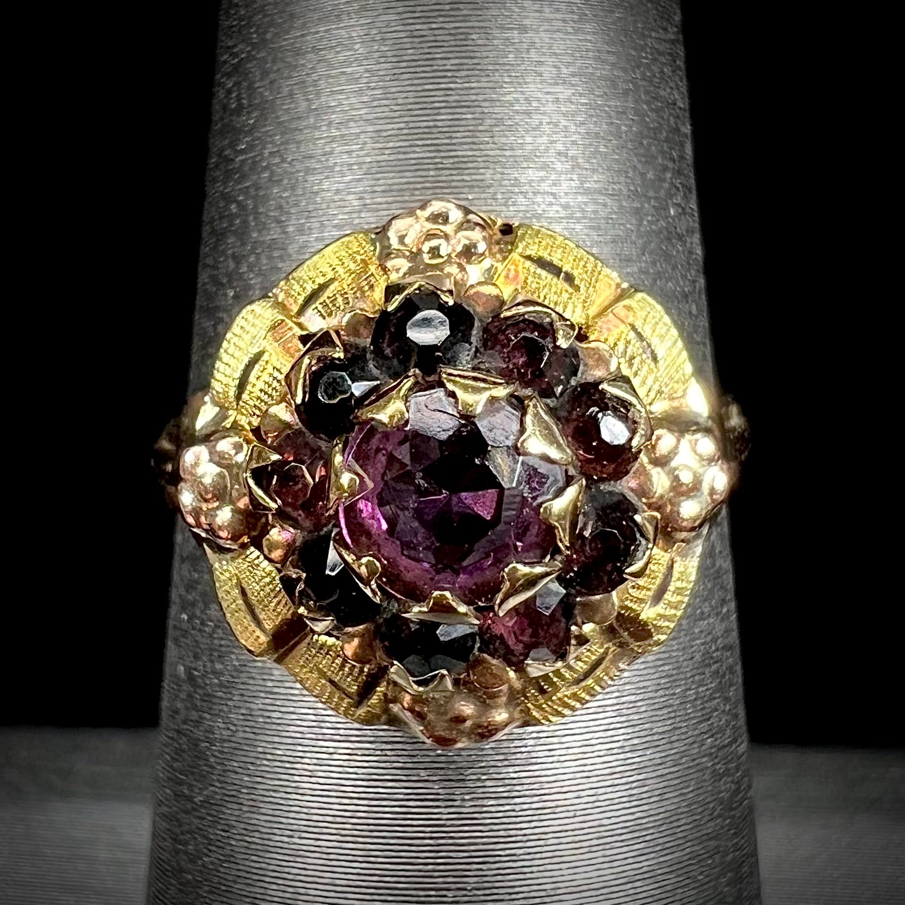 A ladies' Art Nouveau style rhodolite garnet halo ring.  Rose gold flowers accent the piece.