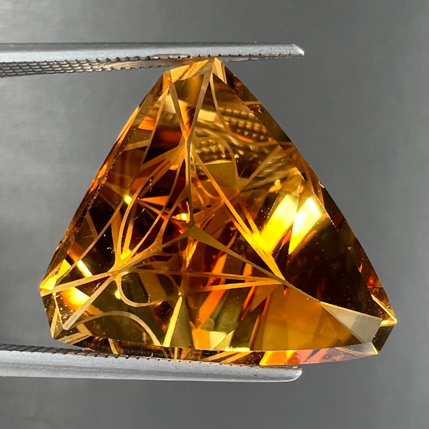 A loose, triangular fantasy cut yellow citrine stone cut by Arthur Lee Anderson.