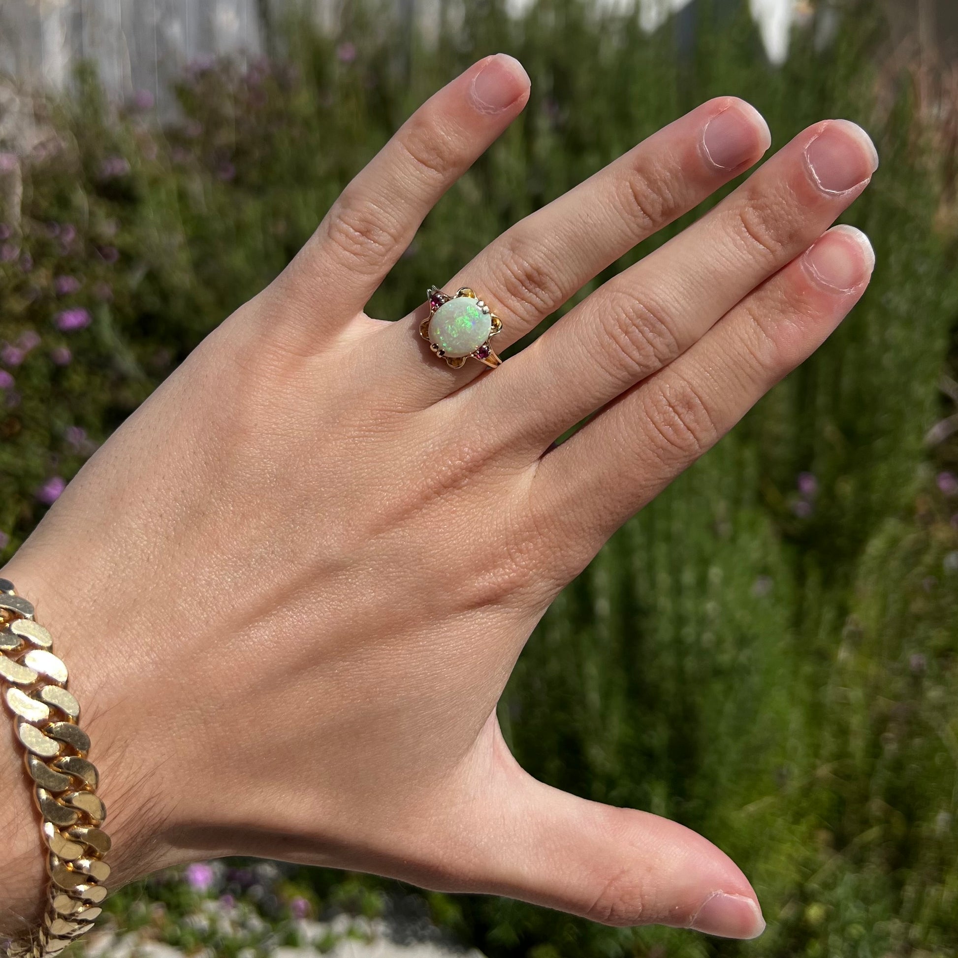 A 1920's Art Nouveau opal and pink sapphire ring.   The ring is yellow gold and palladium.  The opal is green and purple.