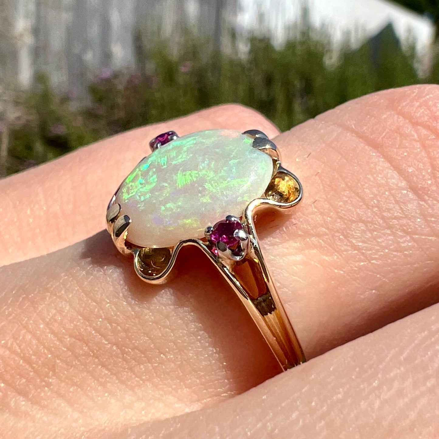 A 1920's Art Nouveau opal and pink sapphire ring.   The ring is yellow gold and palladium.  The opal is green and purple.