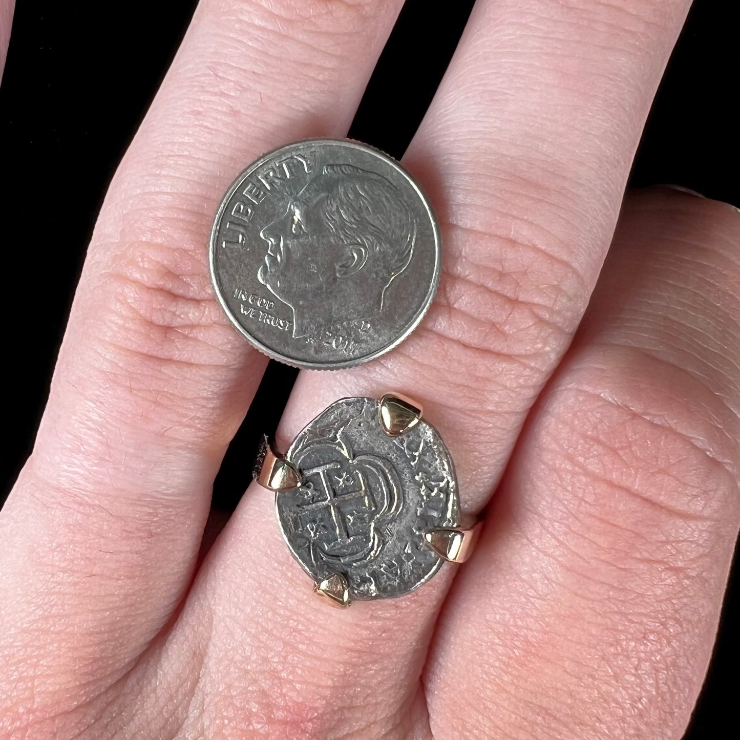 A silver Atocha 1 reale coin replica set in a yellow gold ring.