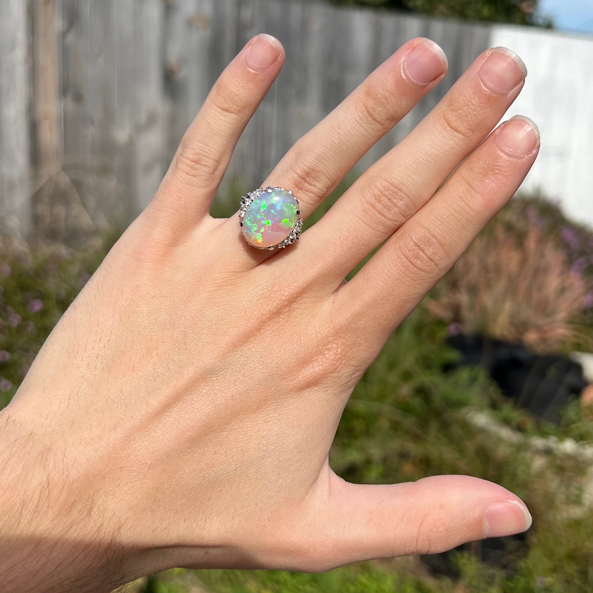 A platinum filigree engagement ring set with a large, green-blue Australian crystal opal.