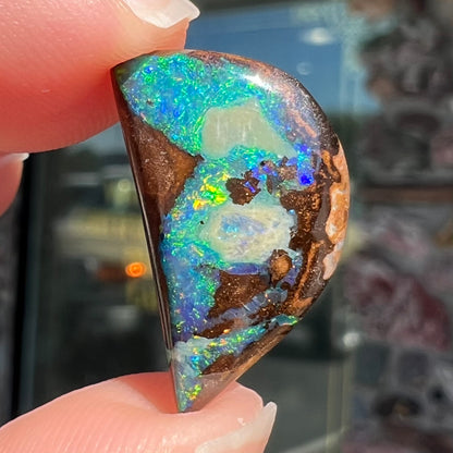 A loose, freeform shaped boulder opal with green and blue multicolor fire from Australia.