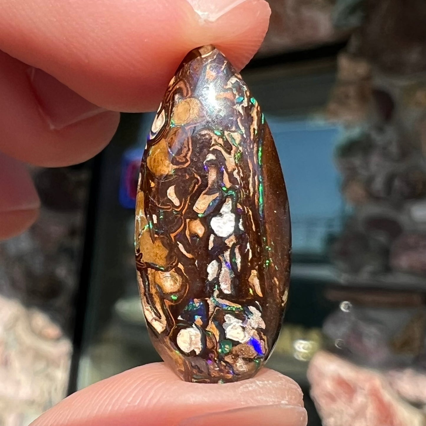 A pear shaped Koroit boulder matrix opal with blue and purple colors in veins.