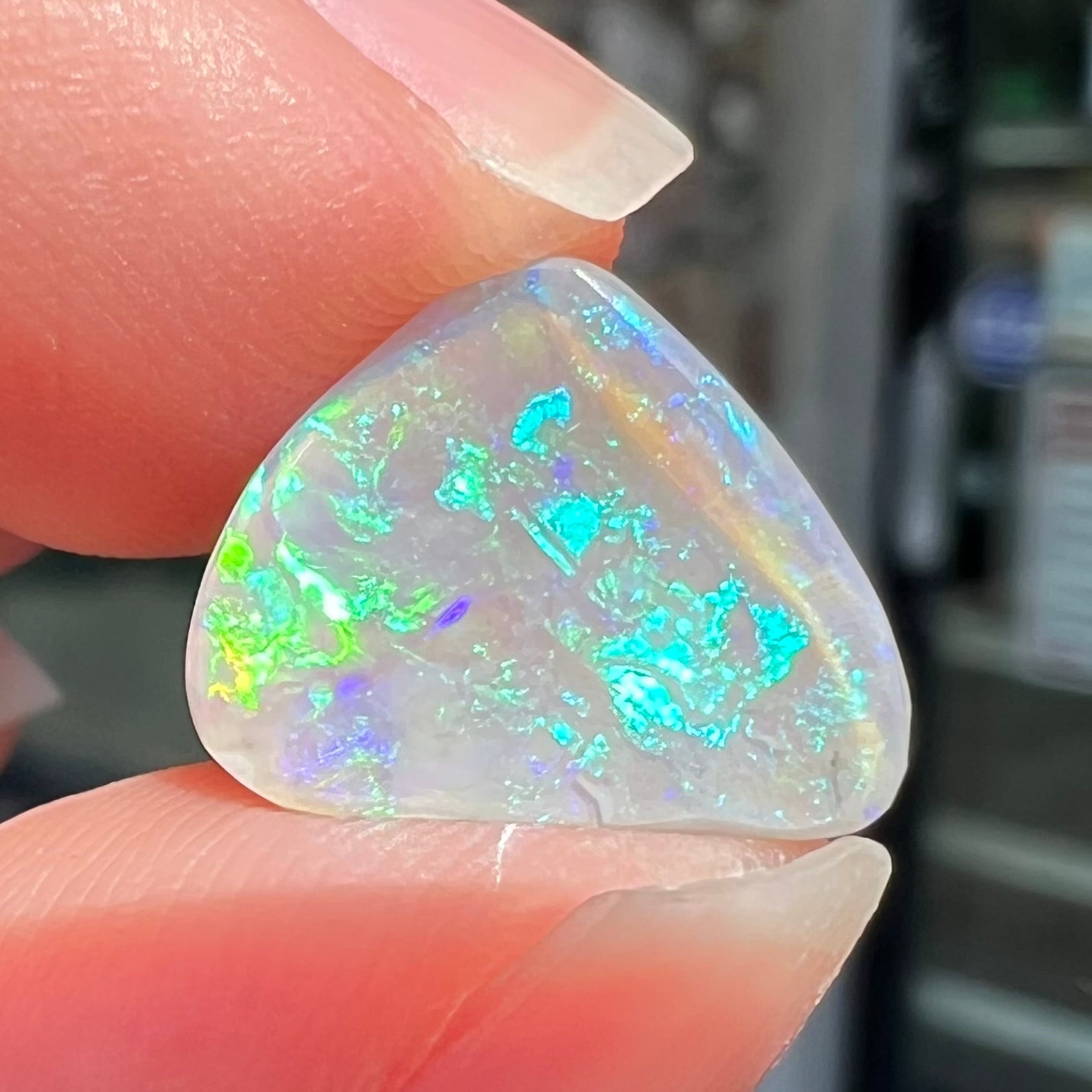 A freeform shaped blue-green light opal stone from Lightning Ridge, Australia.