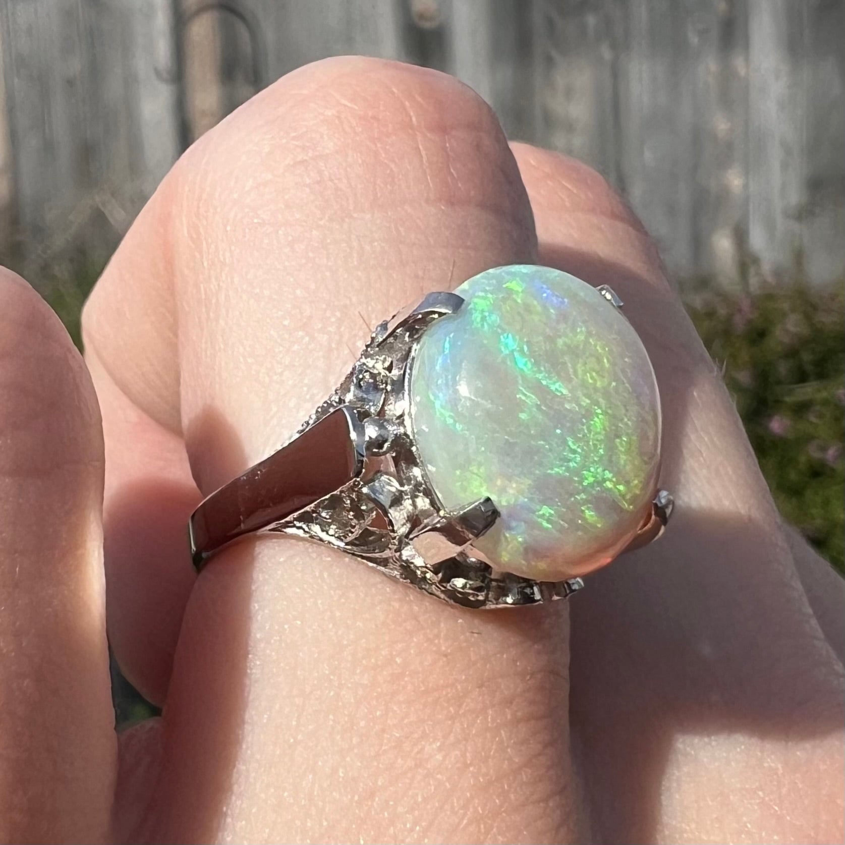 A ladies' Australian opal solitaire engagement ring mounted in platinum.  The opal has green and blue colors.