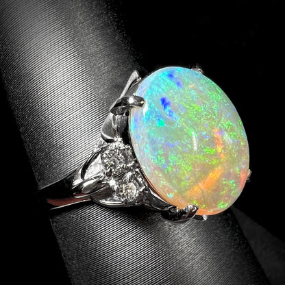 An Australian crystal opal and diamond engagement ring set in a platinum filigree mounting.  The opal plays green/blue colors and has a crack.