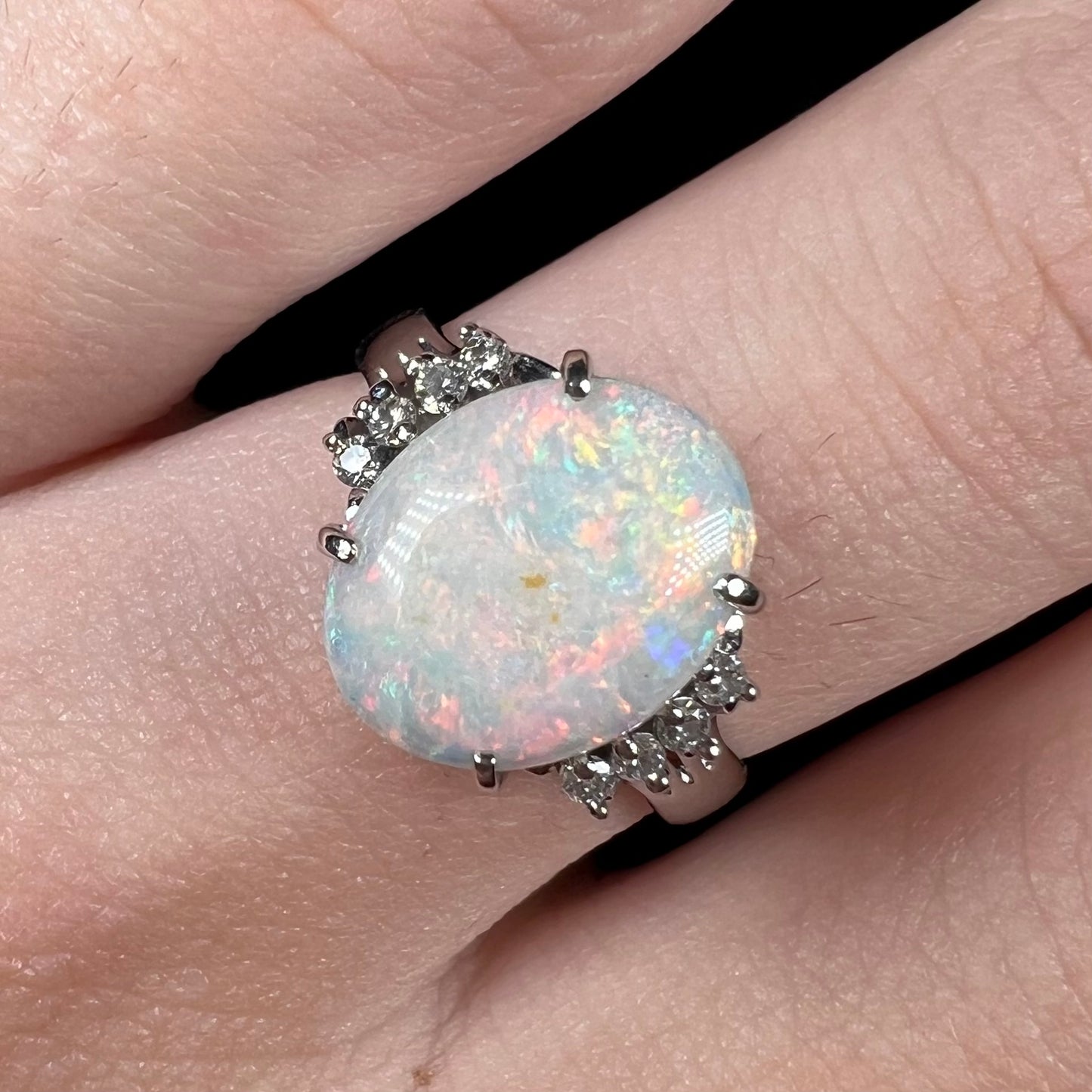 An Australian opal and diamond engagement ring in platinum.  The ring has filigree scrolling.