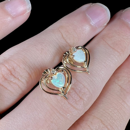 A pair of heart shaped, yellow gold opal stud earrings.  The top of the earrings have a diamond accent.