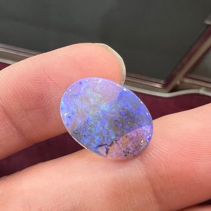 A loose, oval cabochon cut crystal opal from Lightning Ridge, Austalia that weighs 5.16 carats.  The stone has blue and purple colors.