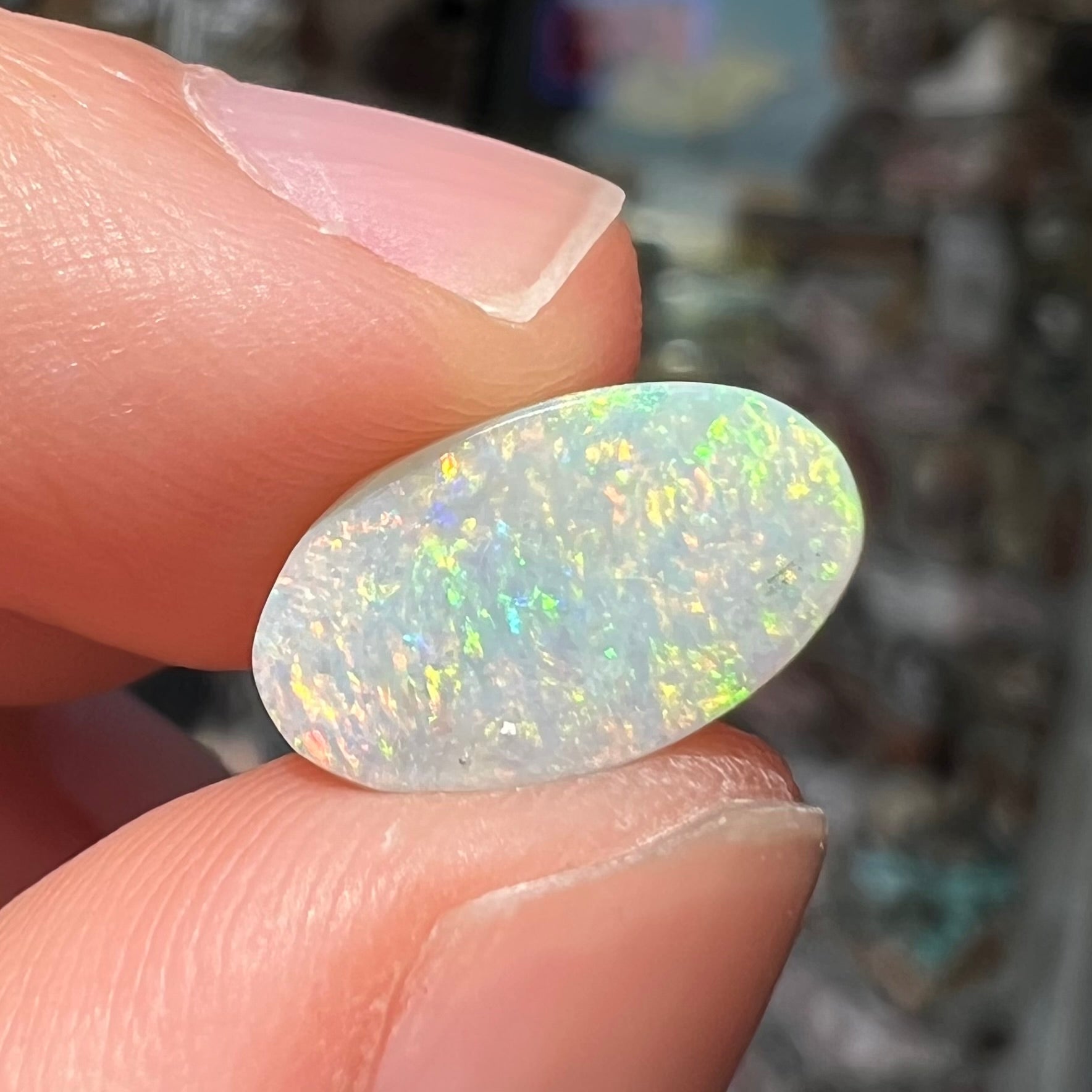 A loose, oval cabochon cut white opal stone from Coober Pedy, Australia.