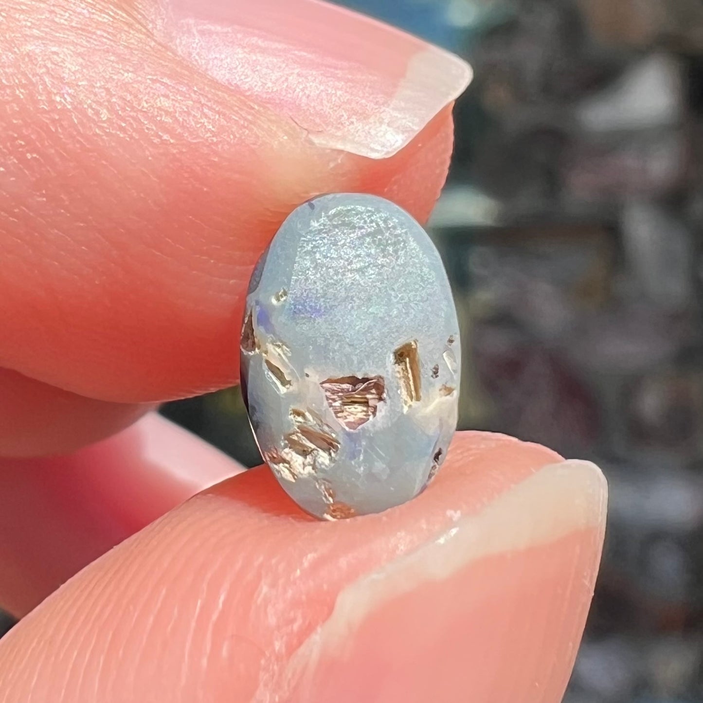 The back of a loose, oval cabochon cut black opal stone from Lightning Ridge, Australia.