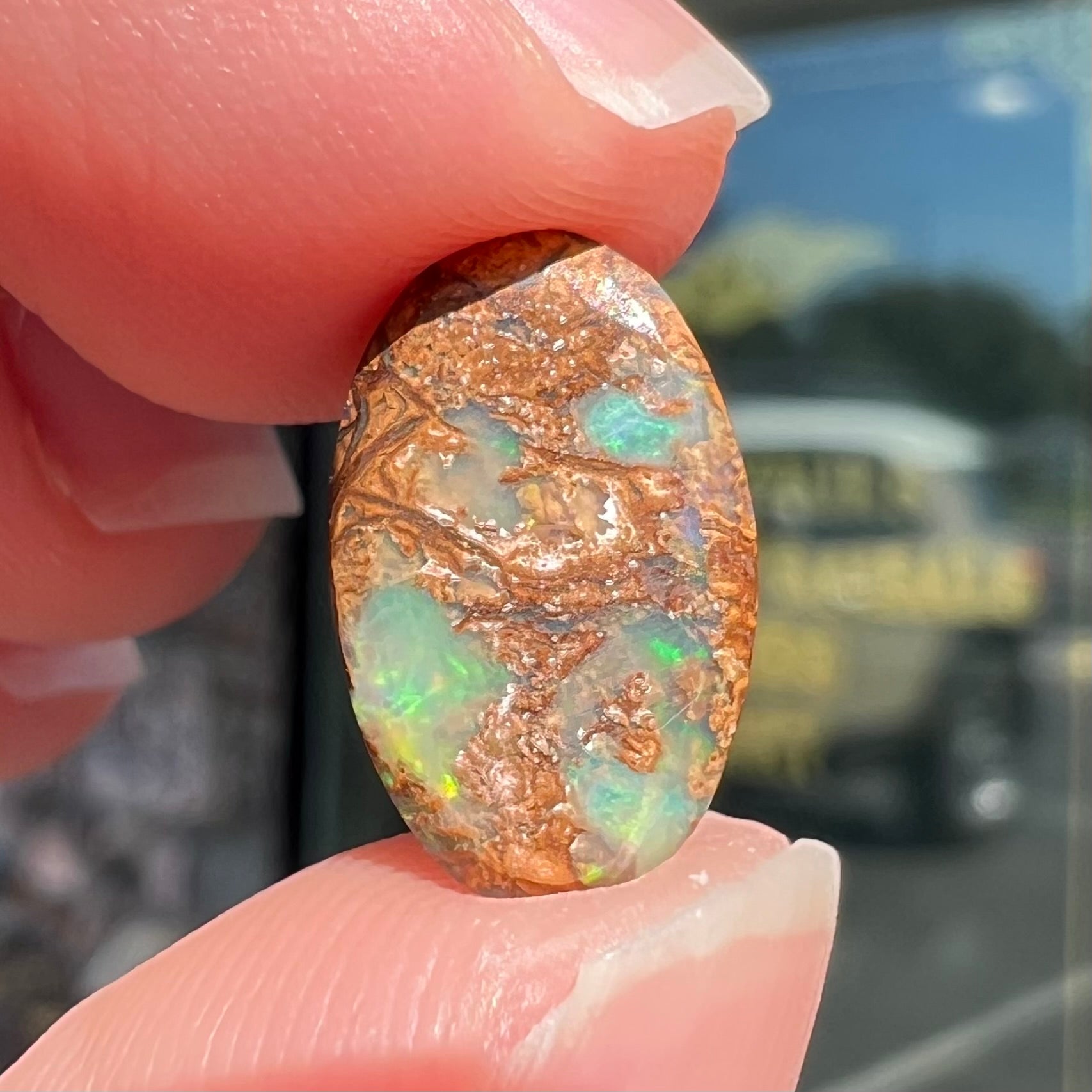 A loose, oval cabochon cut Koroit boulder opal with green fire.