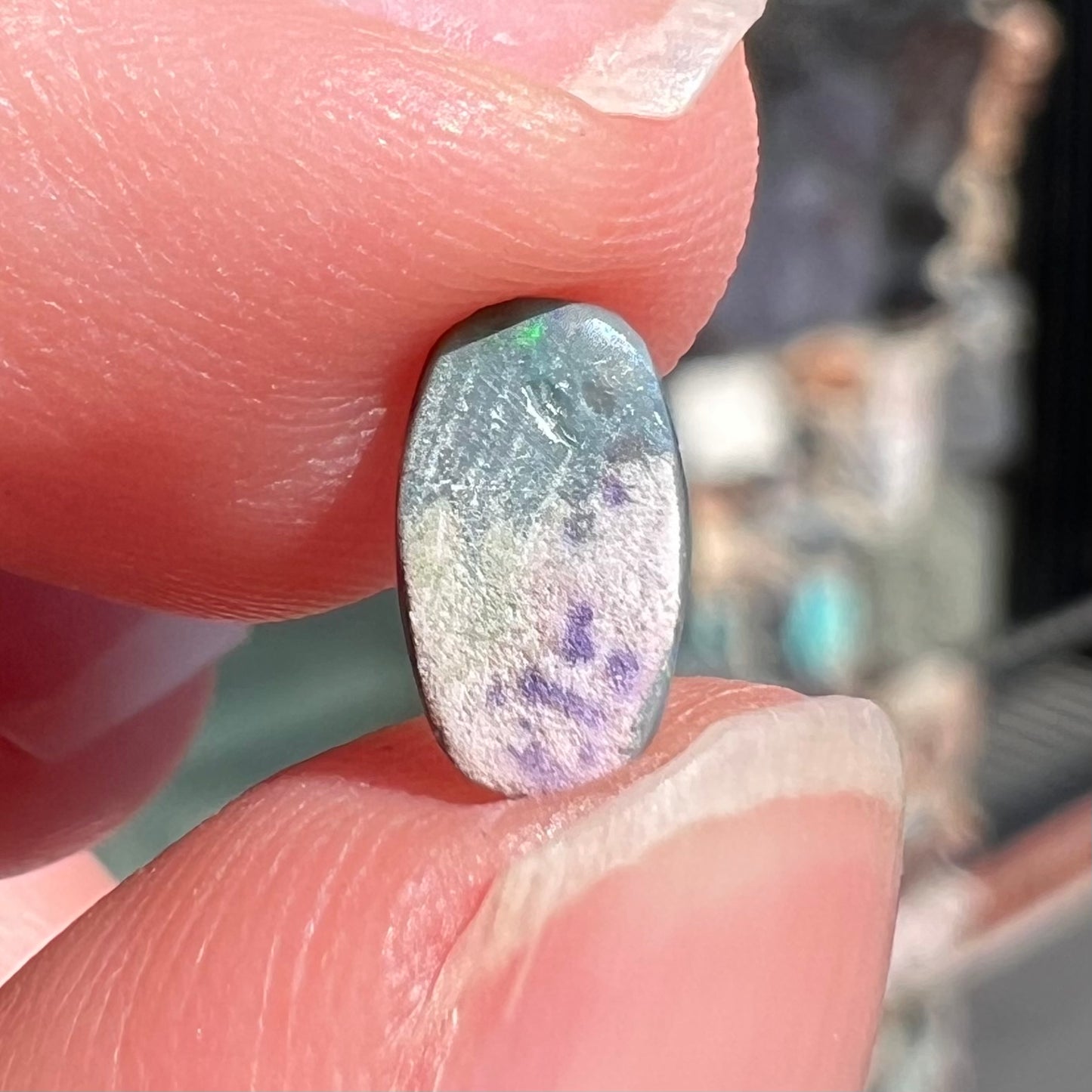 A loose, barrel shaped black opal stone from Lightning Ridge, Australia.