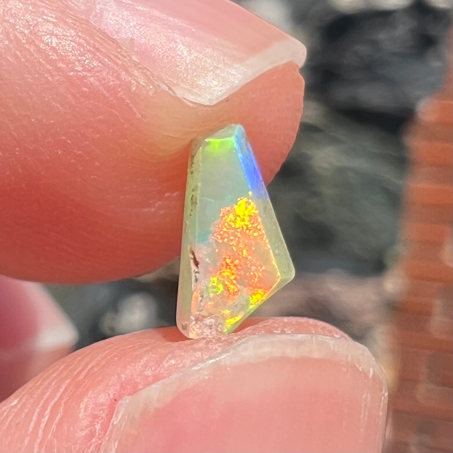 A loose, Australian fire opal chip.  The stone shines red, green, and yellow colors.