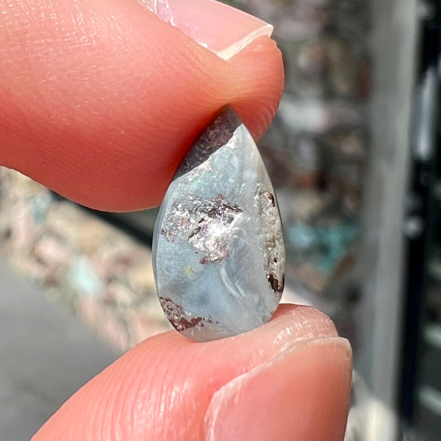 A loose, pear shaped Australian opal stone.  The opal shows green and blue colors.