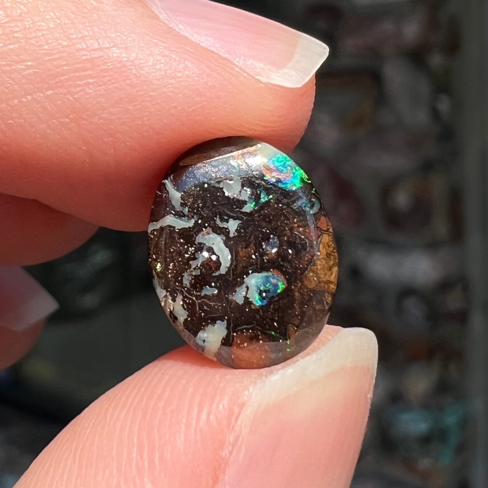 A loose, oval cabochon cut boulder opal stone from Koroit, Australia.  The opal has a bright green flash.