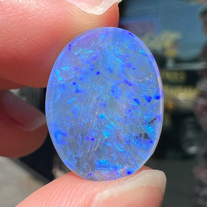 A loose, oval cabochon cut crystal opal from Lightning Ridge, Austalia that weighs 5.16 carats.  The stone has blue and purple colors.