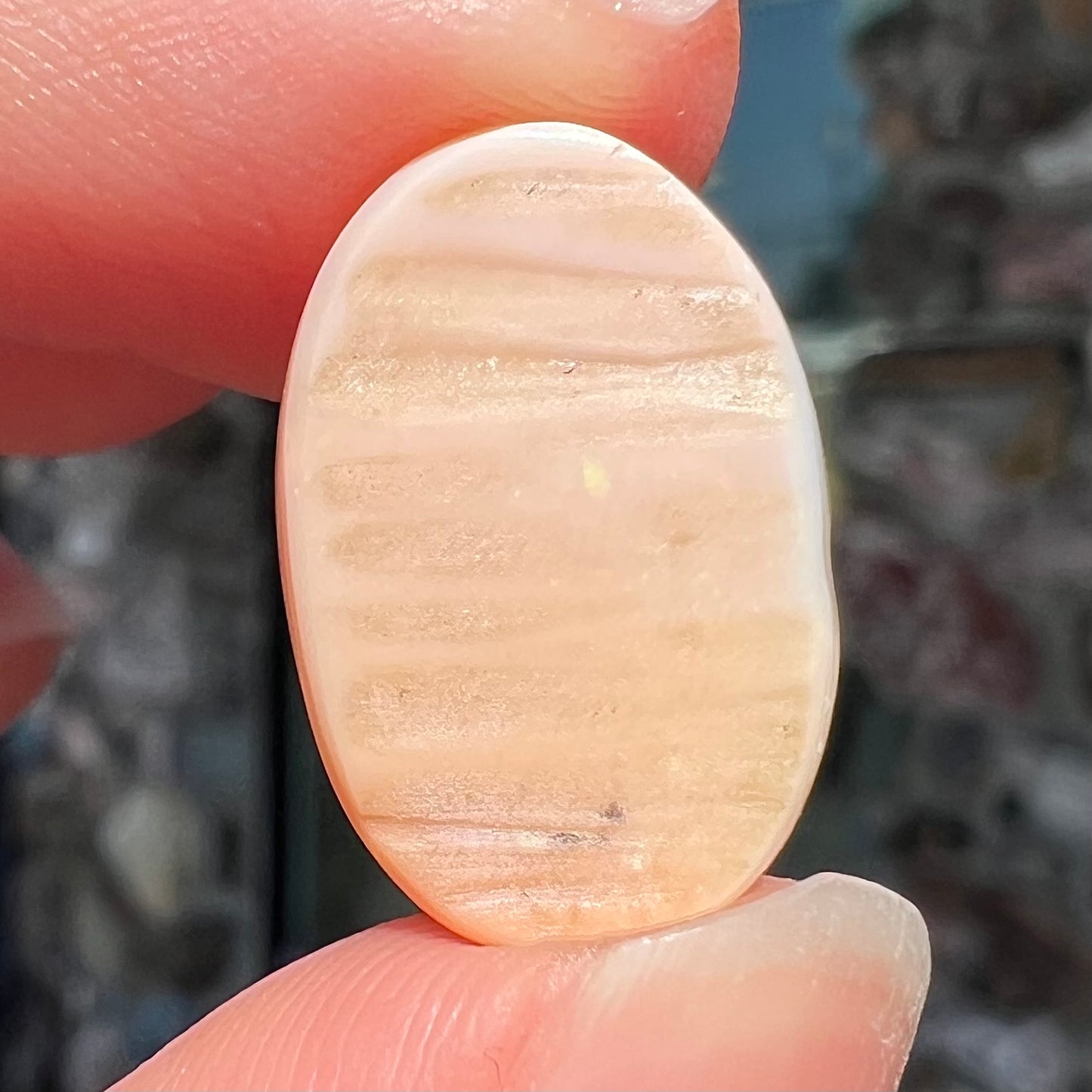 A loose, oval cabochon cut Peruvian opal stone.  The opal is a coral pink color.