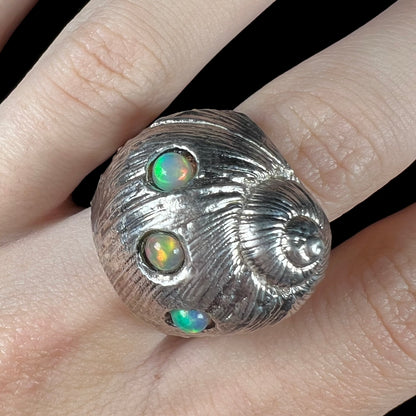 A large, three dimensional sterling silver snail seashell ring set with three round Ethiopian fire opal stones.