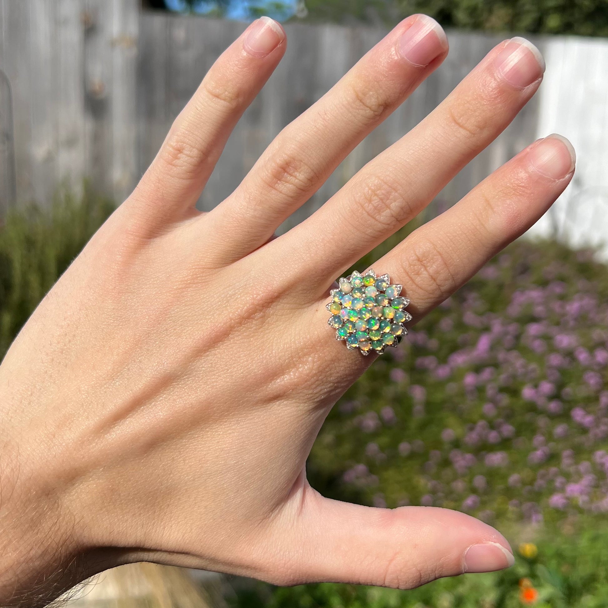 A sterling silver cluster flower ring mounted with 33 round Ethiopian fire opals.