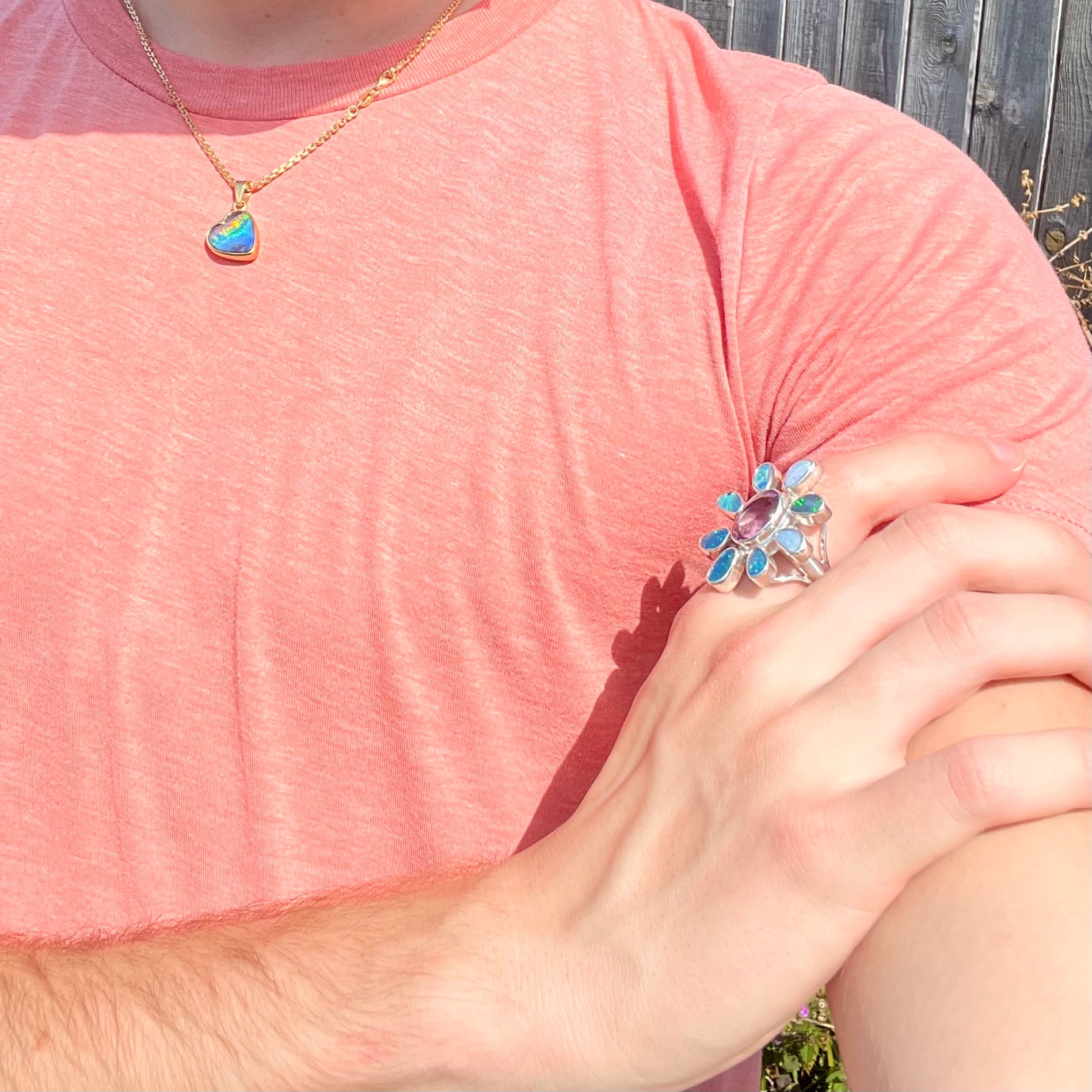 A sterling silver flower shaped ring set with an oval cut amethyst in the center and black opal doublet petals.