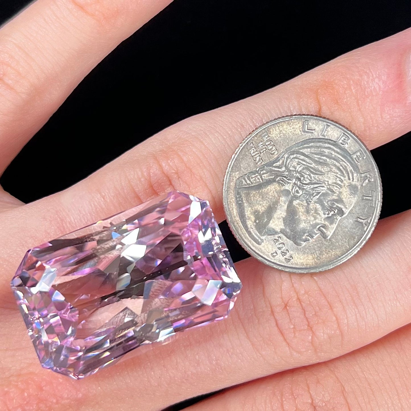 A loose, radiant cut kunzite gemstone.  The stone is a light purplish pink color.