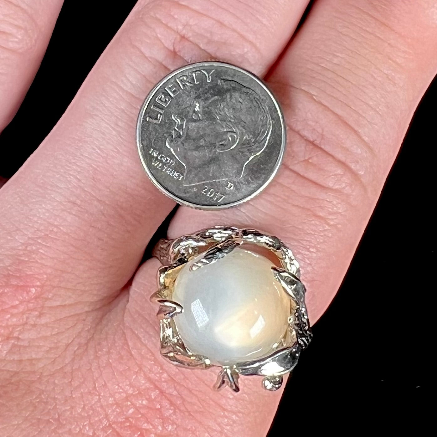 A ladies' organic style white gold moonstone ring.  The moonstone shows white adularescence on a creamy white body color.  Prongs resemble leaves holding the stone.