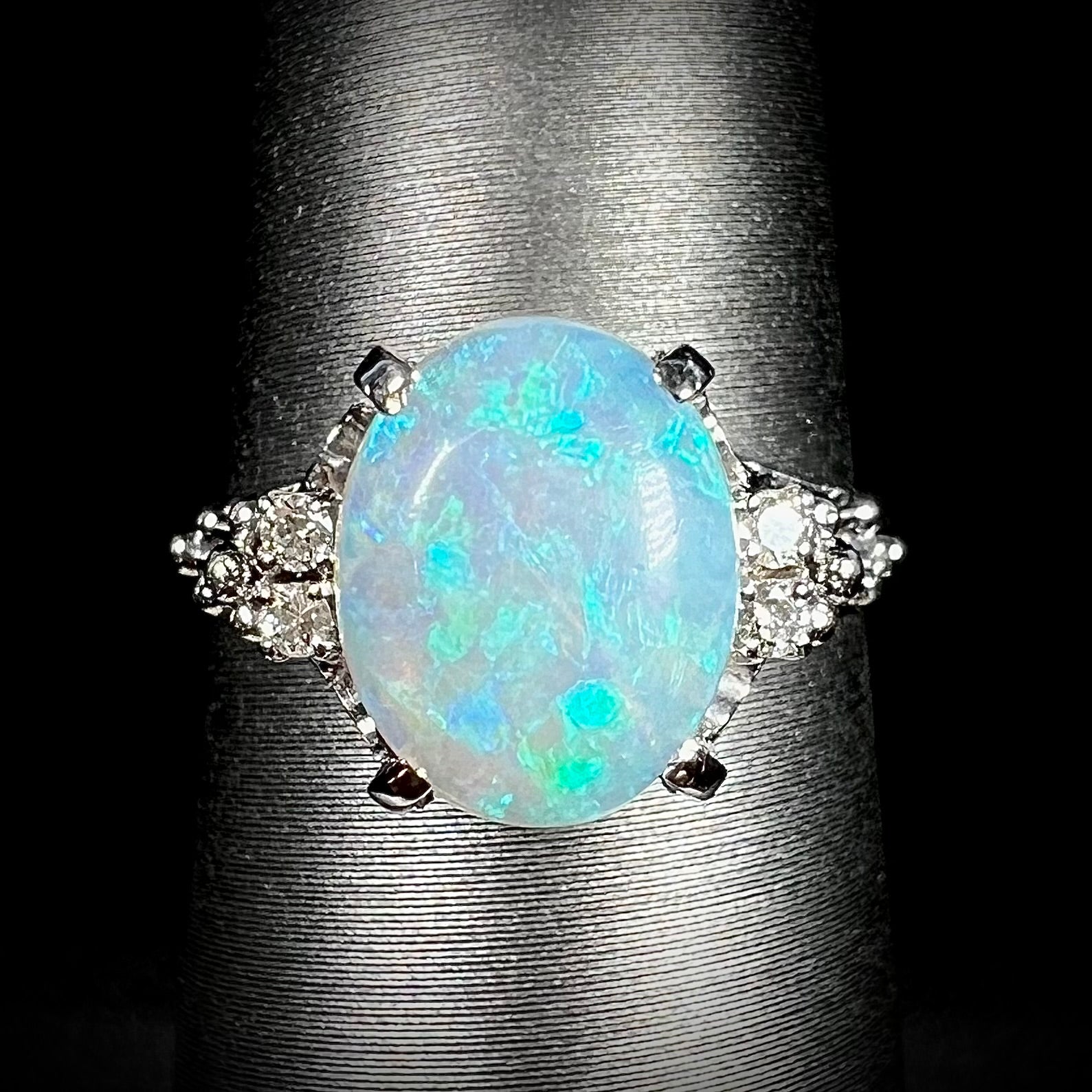 A platinum filigree ring mounted with a blue-green crystal opal and diamond accents.