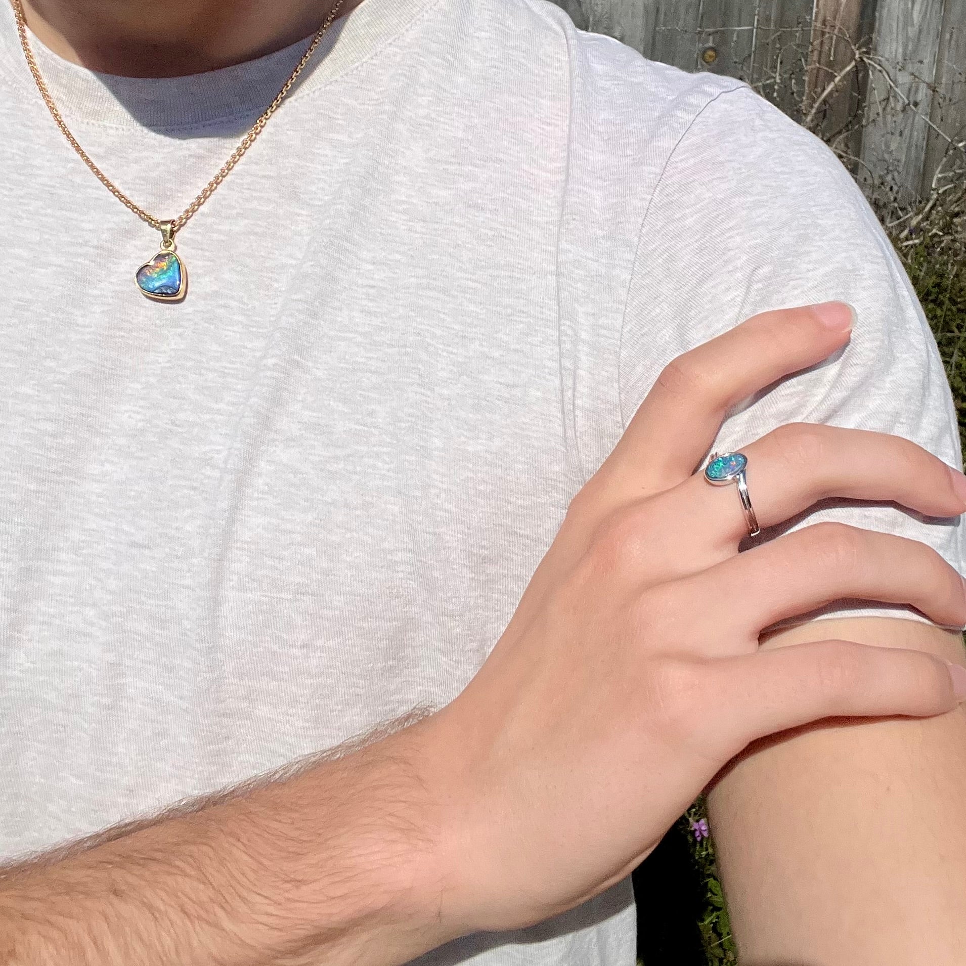 A sterling silver ring bezel-set with an oval shaped black opal doublet.  The opal has red and blue fire.