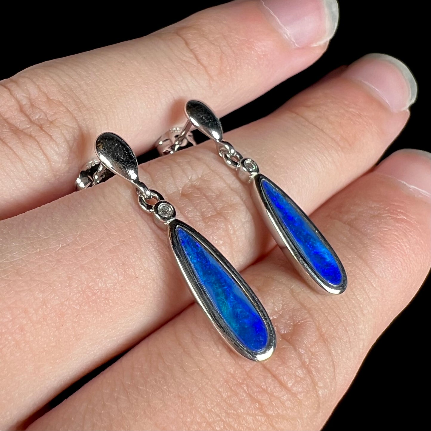 A pair of sterling silver dangle earrings mounted with pear shaped black opal doublets.