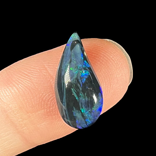 A freeform pear shaped black opal from Lightning Ridge, Australia.