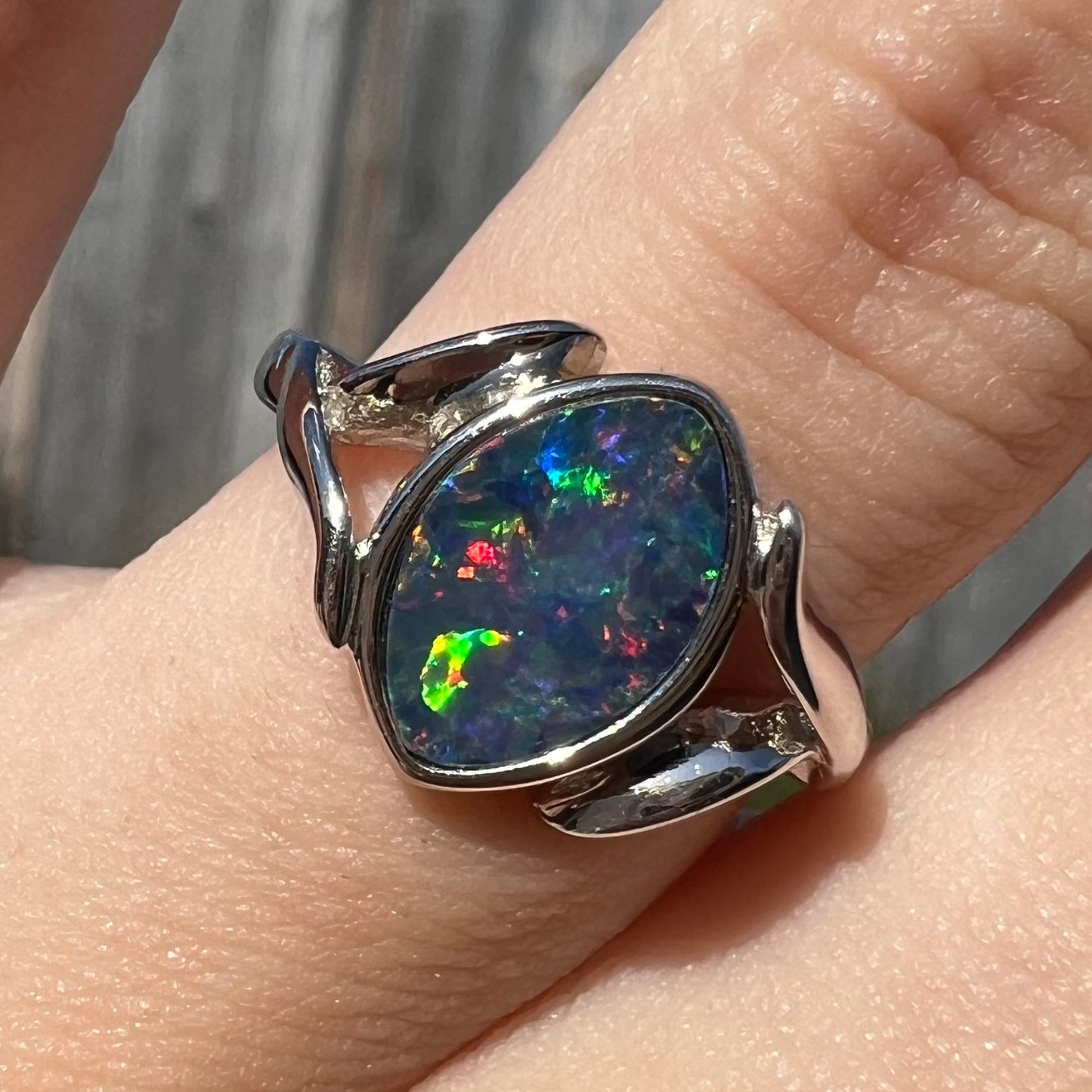 A sterling silver ring mounted with a marquise cut black opal doublet.  The opal has red fire.