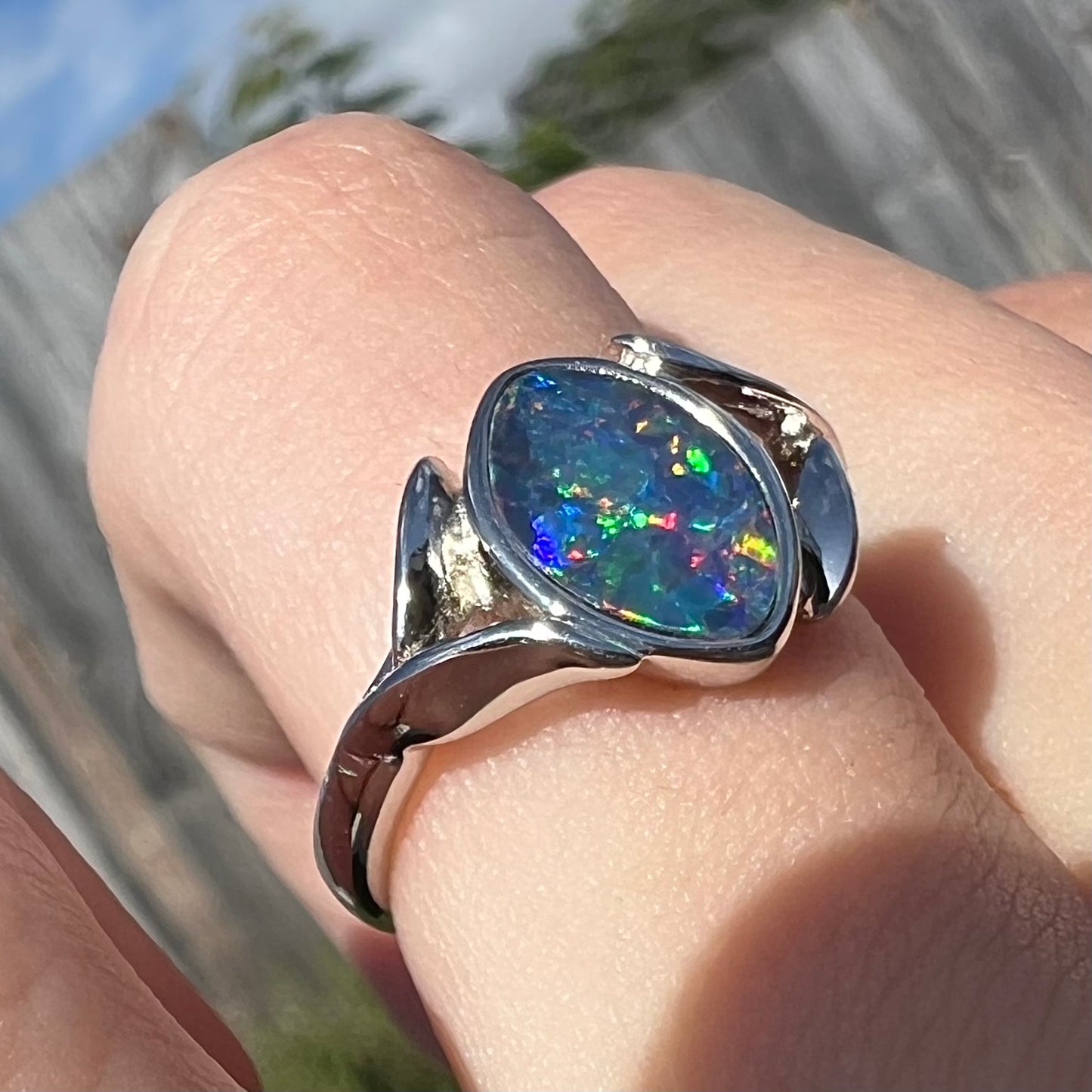 A sterling silver ring mounted with a marquise cut black opal doublet.  The opal has red fire.