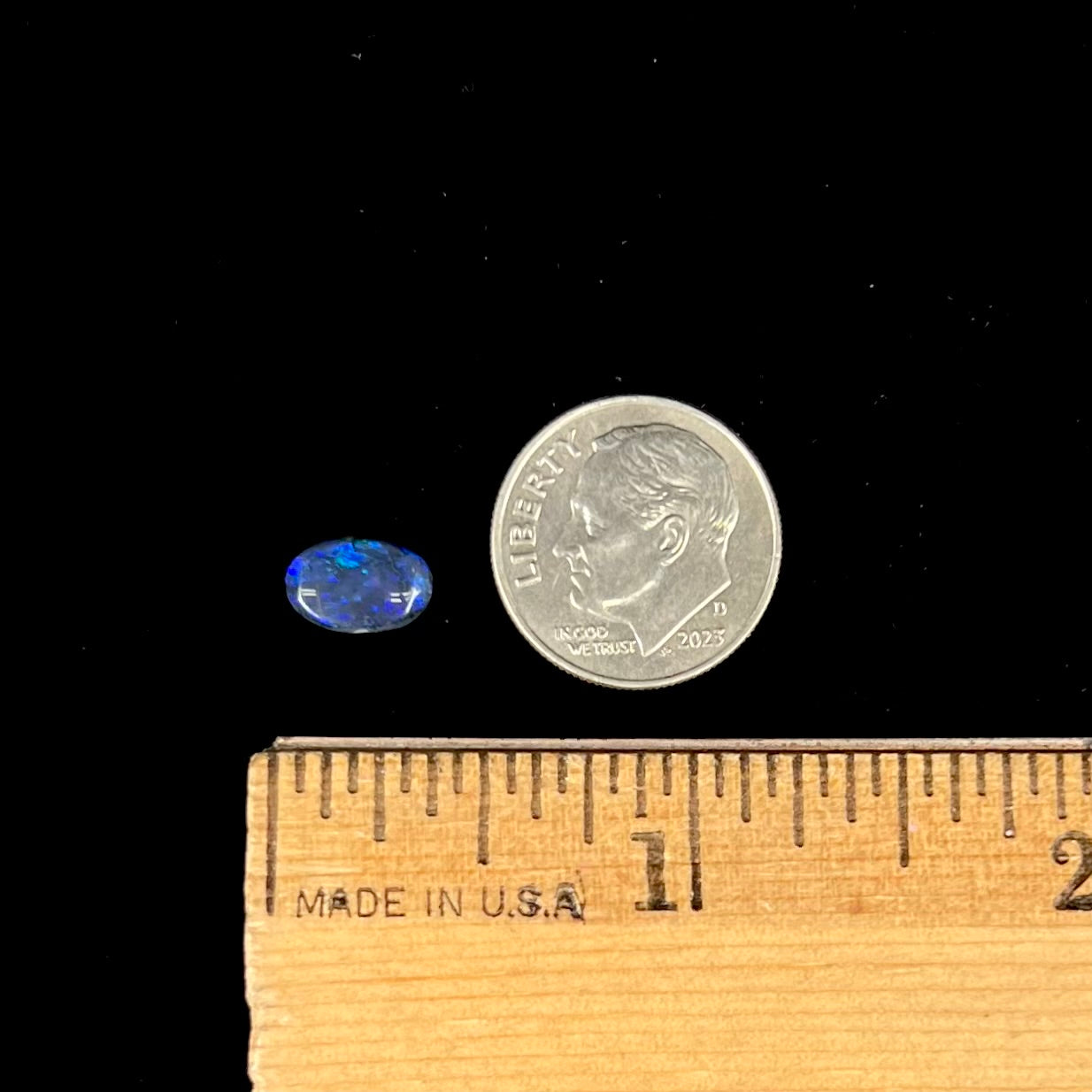 A loose, oval cabochon cut black opal stone from Lightning Ridge, Australia.  The opal has blue color play.