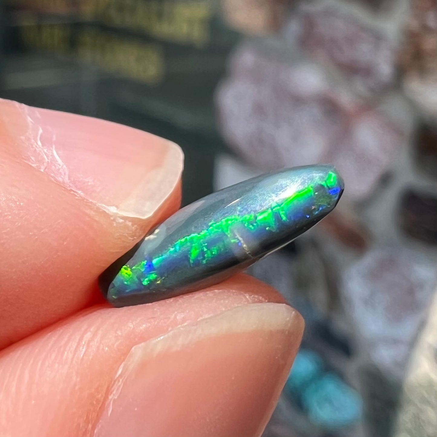 A loose, elongated oval cut black opal that has a green and blue cat's eye.