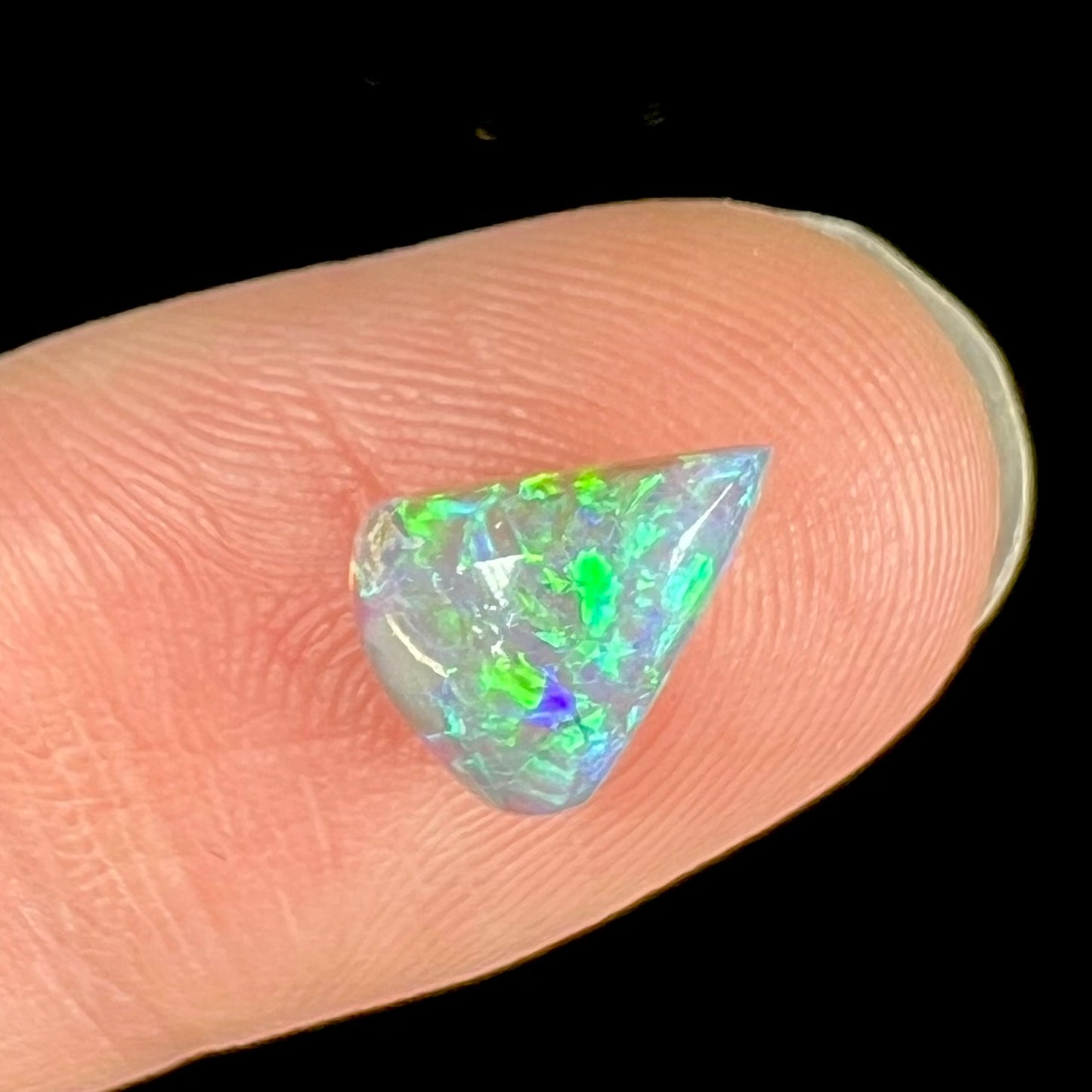 A pear shaped semi-black crystal opal with green fire.