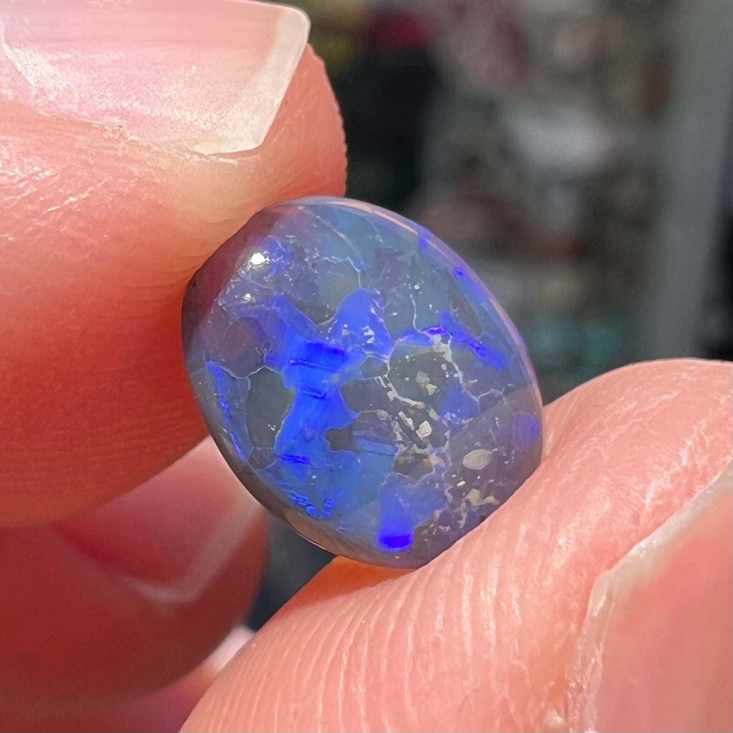 A loose, oval cabochon cut black crystal opal from Lightning Ridge, Australia.