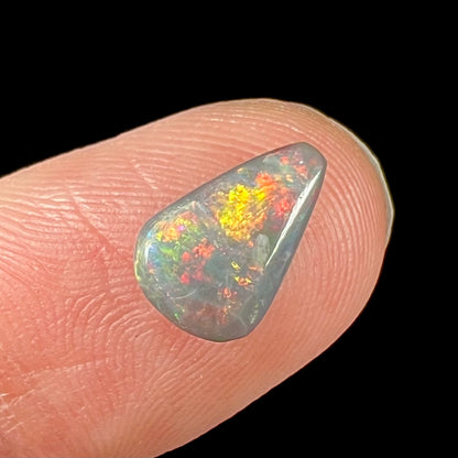 A loose, pear shaped black opal stone with red fire.