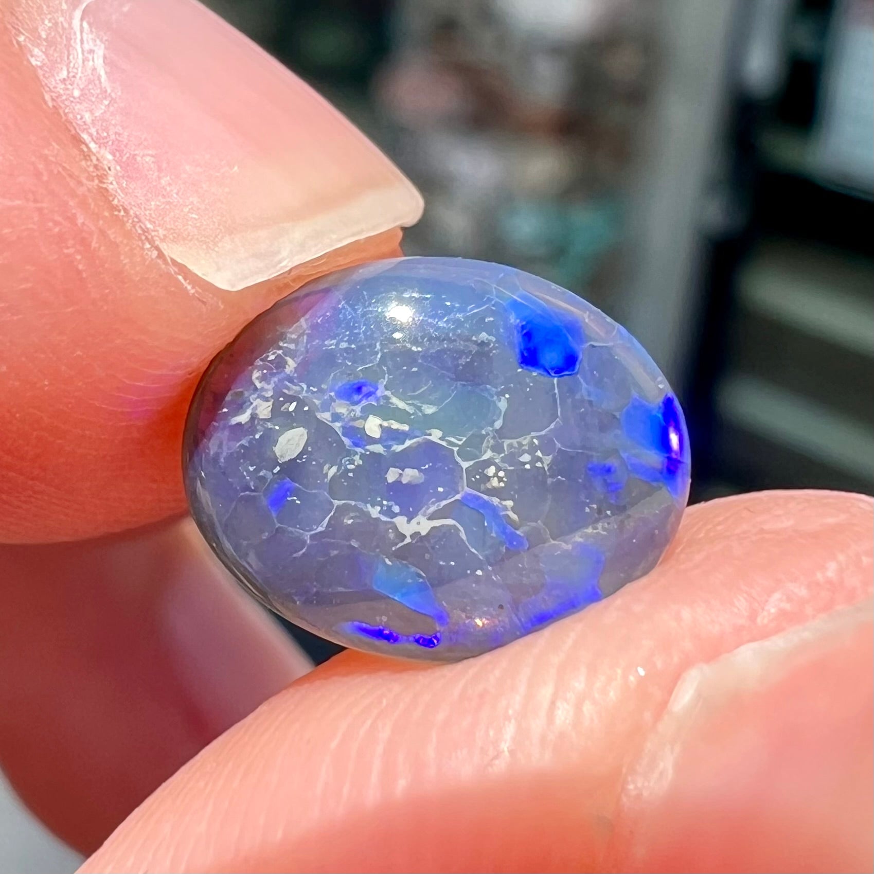 A loose, oval cabochon cut black crystal opal from Lightning Ridge, Australia.