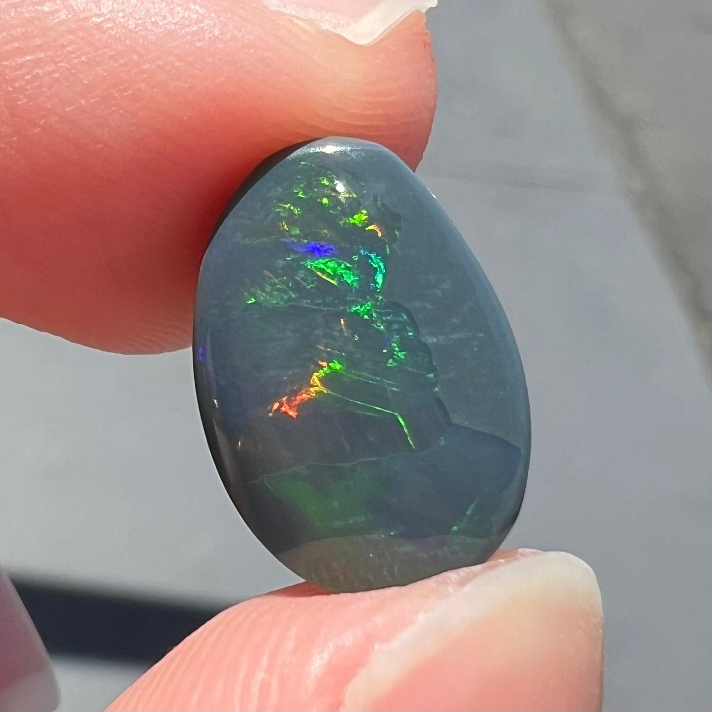 A loose, freeform cut black opal stone from Lightning Ridge, Australia.