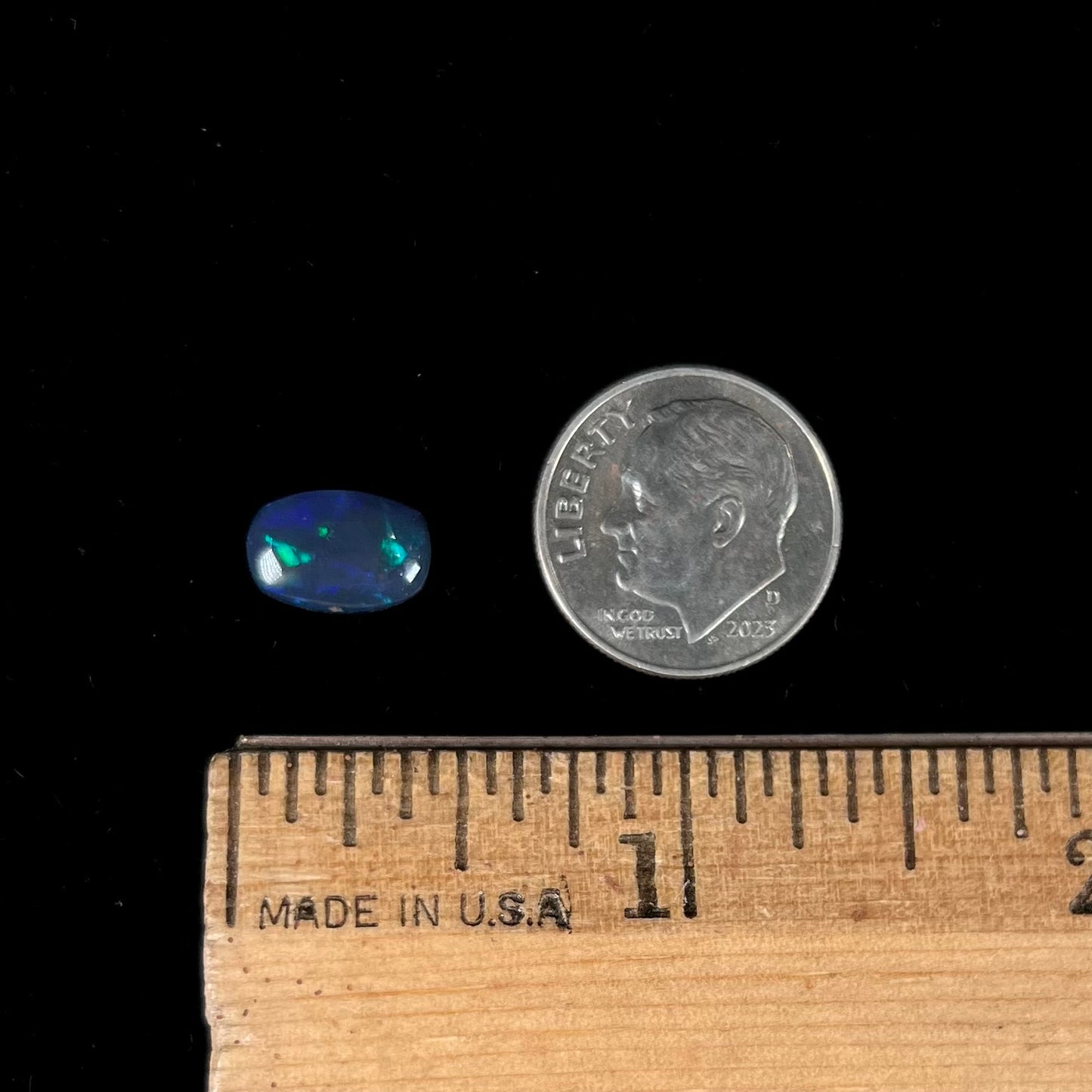 A loose Lightning Ridge black opal stone that shines colors of green, blue, and purple.