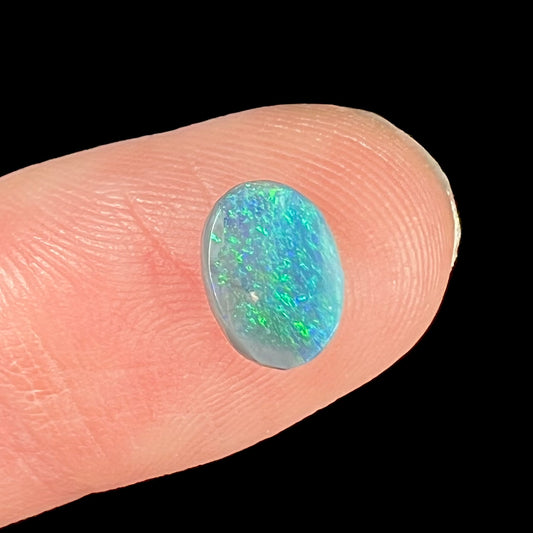 An oval cabochon cut loose Black opal stone from Lightning Ridge, Australia.