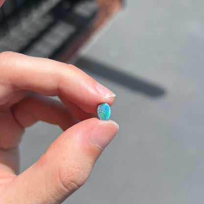 An oval cabochon cut loose Black opal stone from Lightning Ridge, Australia.