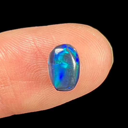 A loose black opal from Lightning Ridge, Australia.  The opal displays a blue cat's eye pattern.