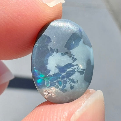 A loose, freeform cut black opal stone from Lightning Ridge, Australia.