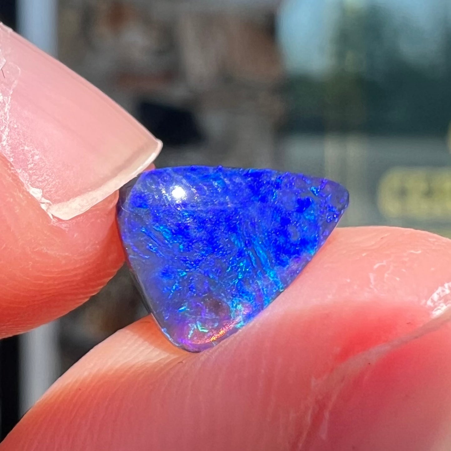 A loose, triangular cut black semi-crystal stone.