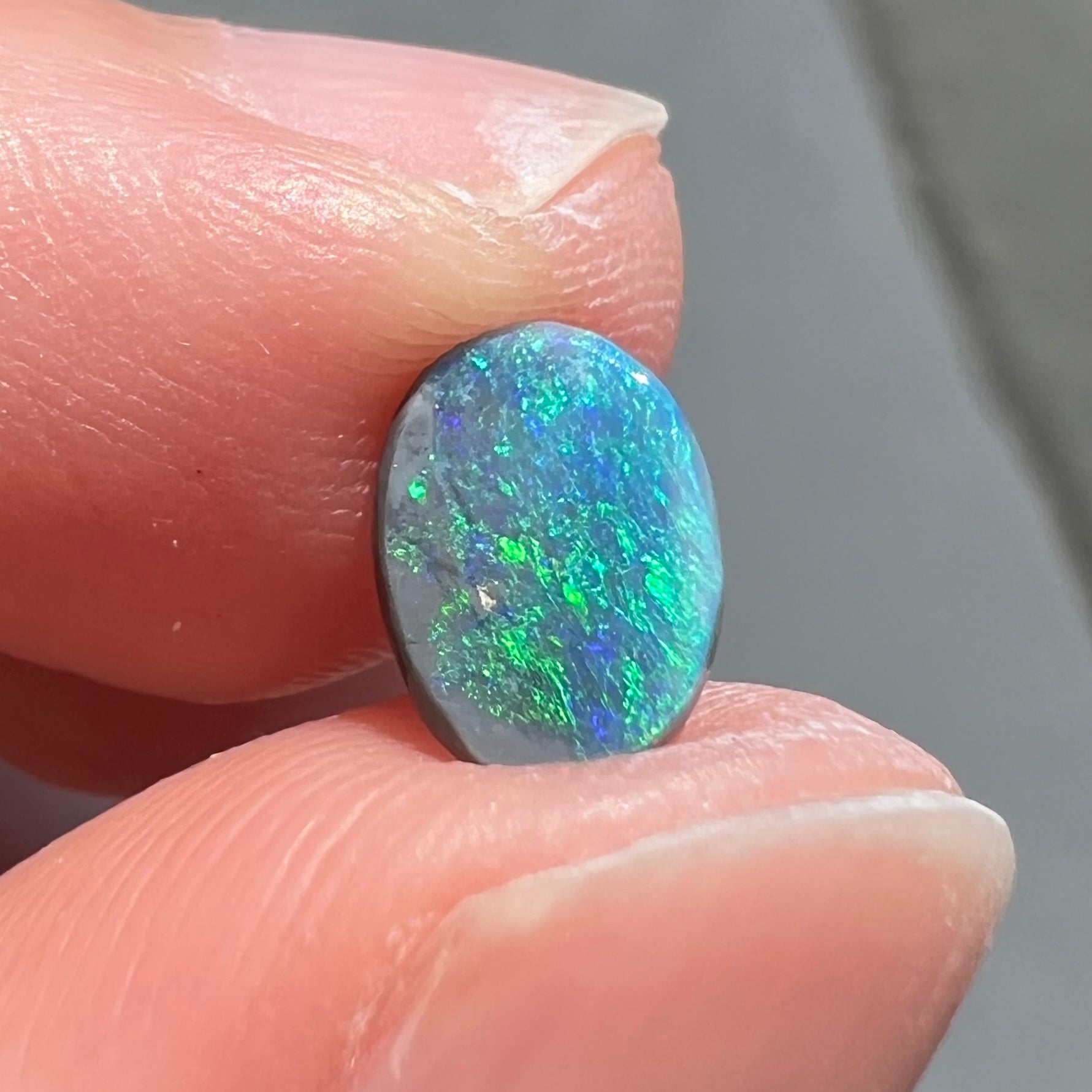 An oval cabochon cut loose Black opal stone from Lightning Ridge, Australia.