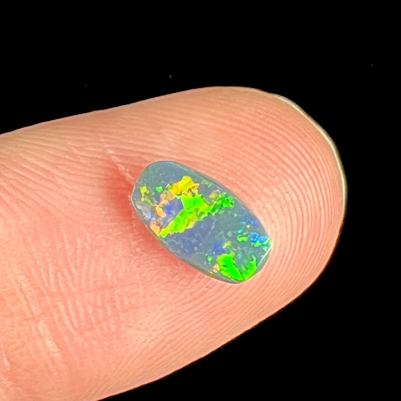 A loose, barrel shaped black opal stone from Lightning Ridge, Australia.