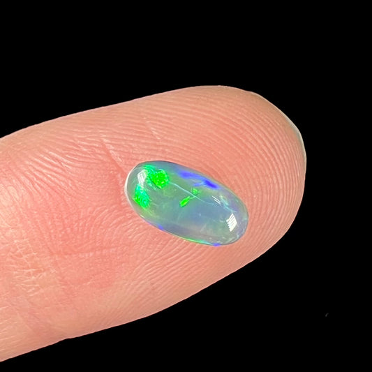 A loose, pill shaped black opal stone from Lightning Ridge, Australia.  The opal is green and blue.